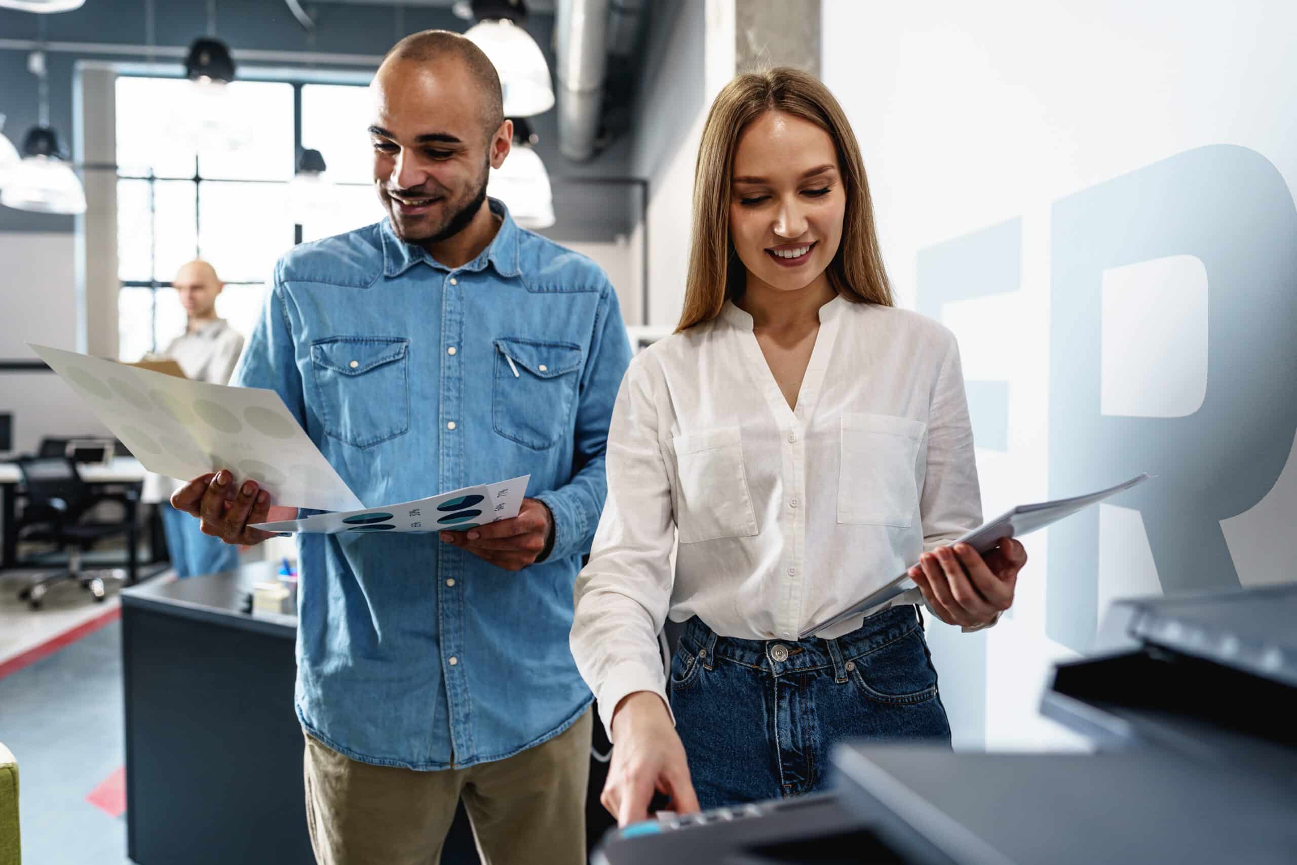 Mannelijke en vrouwelijke collega bekijken printouts bij printer